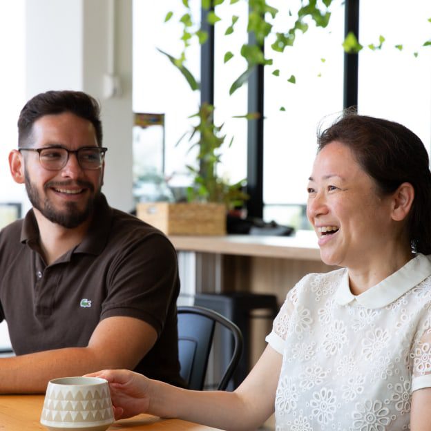 Two people sitting at cafe table. Both people are smiling.