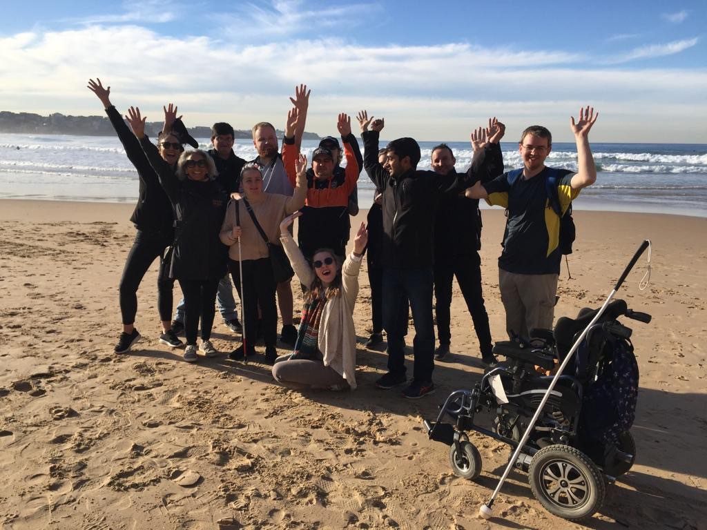 A group of people on a beach facing the camera with their arms in the air