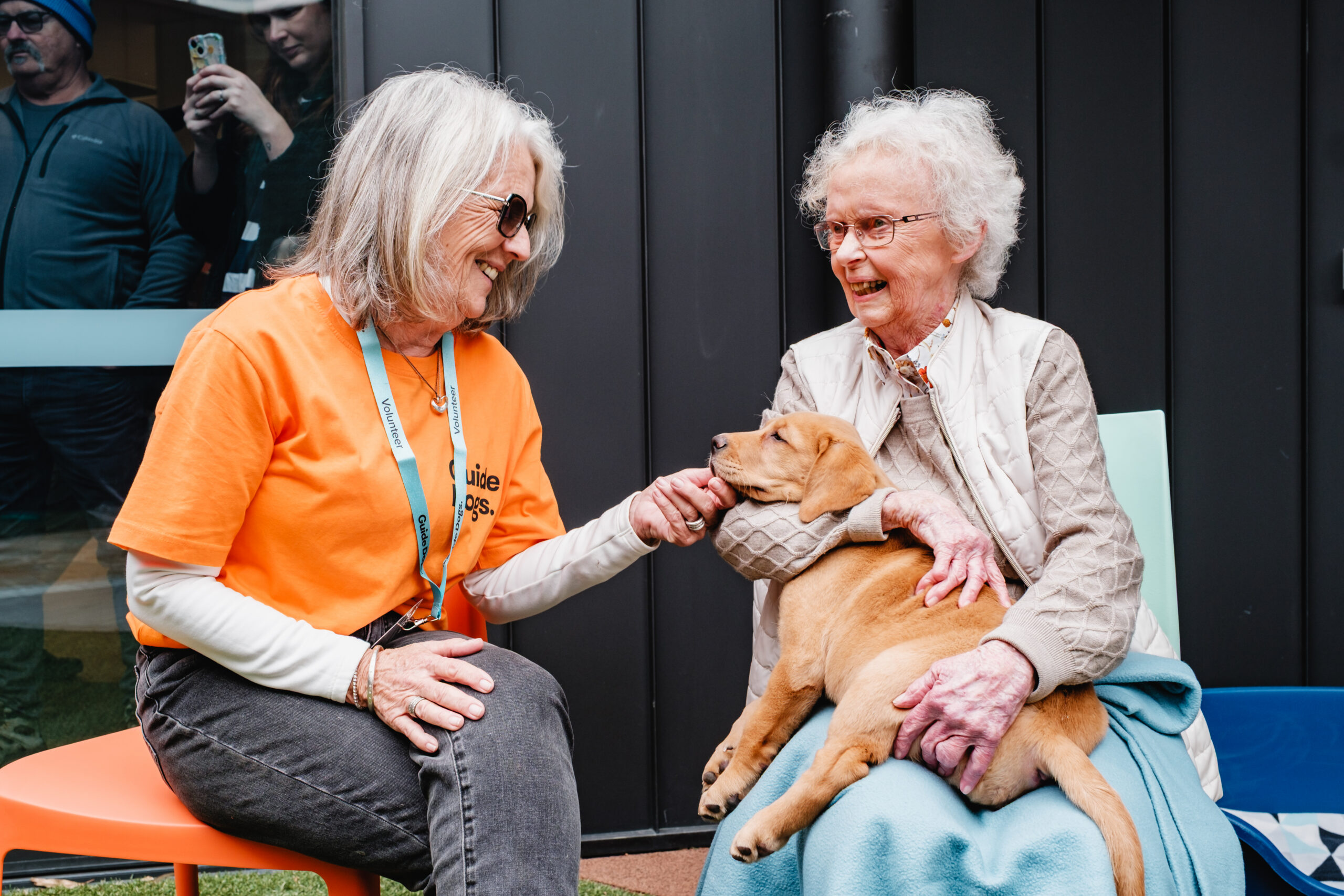 Guide Dogs Volunteer with a woman holding a yellow Labrador puppy
