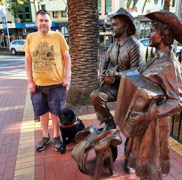 Murray standing next to his seated Guide Dog, Karli