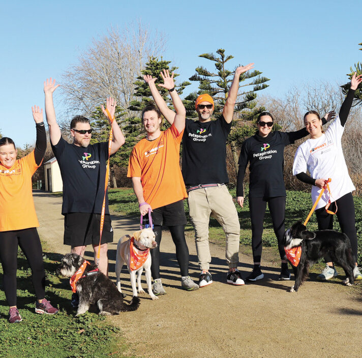 a group of people raising their hands in the air while holding dogs on leads.