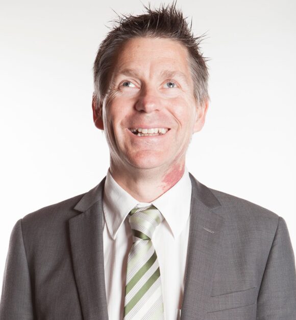 Headshot of Guide Dogs Victoria's Board Chair, Iain Edwards. Iain is looking at the camera smiling.