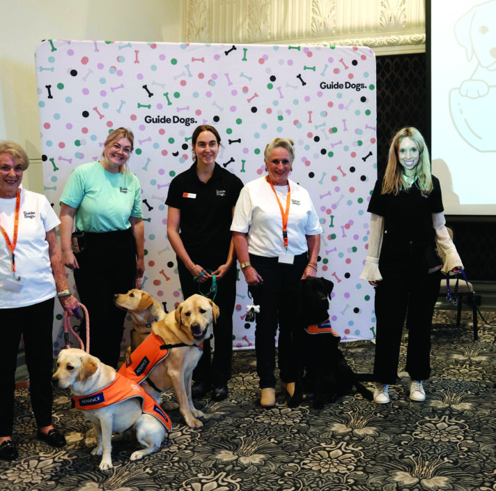A group of people in front of a banner at the International Guide Dog Day celebration