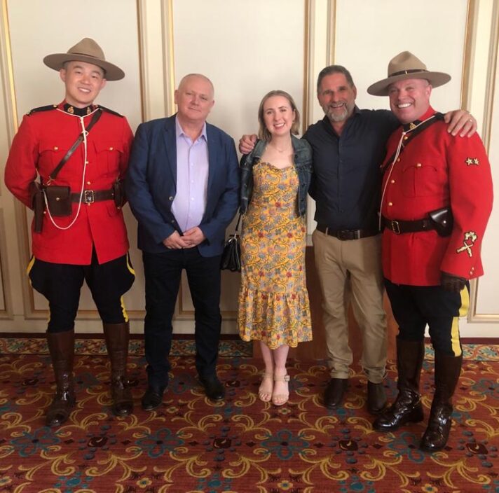Guide Dogs staff Gary, Elisha and Aaron standing in between two Canadian mounted police wearing the Red Serge uniform