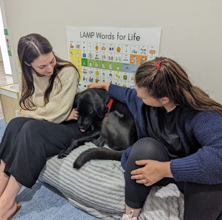 Nessie cuddling in between two people in a clinic.