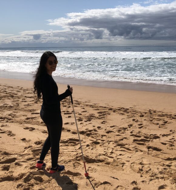 Noora on the beach with her white cane
