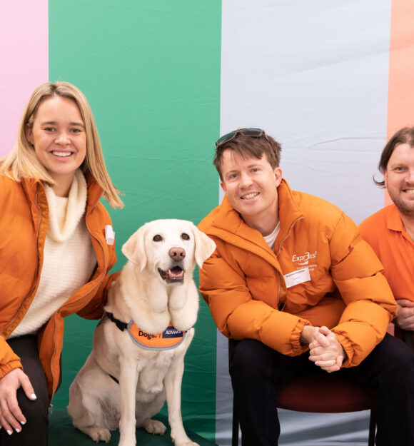 Expr3ss staff members crouch next to a yellow Labrador