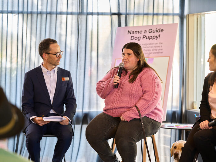 A guest wearing a pink sweater shares her story with everyone at the guide dog event.