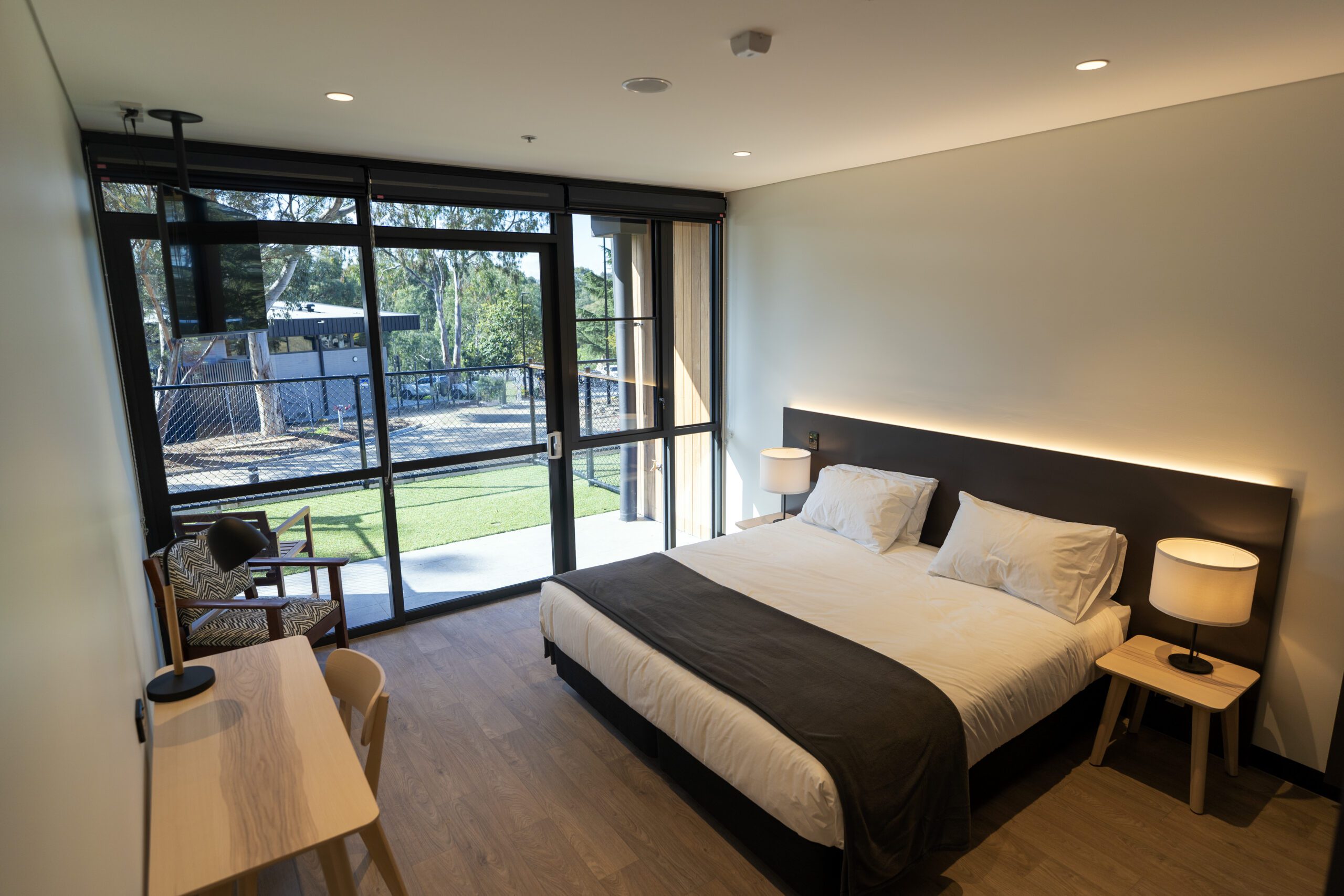 Inside one of the residential accomodation rooms. A bred sits in the centre with a wall of windows to the right.