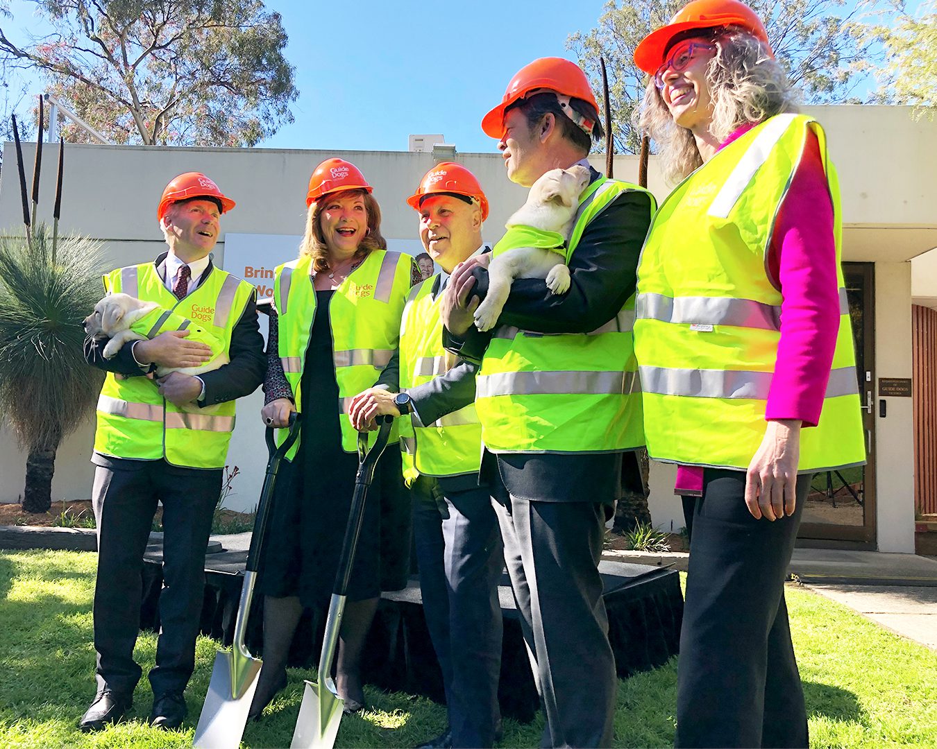 Iain Edwards, Karen Hayes, Tim Pallas MP, Luke Donnellan MP and Nina Taylor stand in High Vis vests with shovels in hand, outside Guide Dogs Victoria