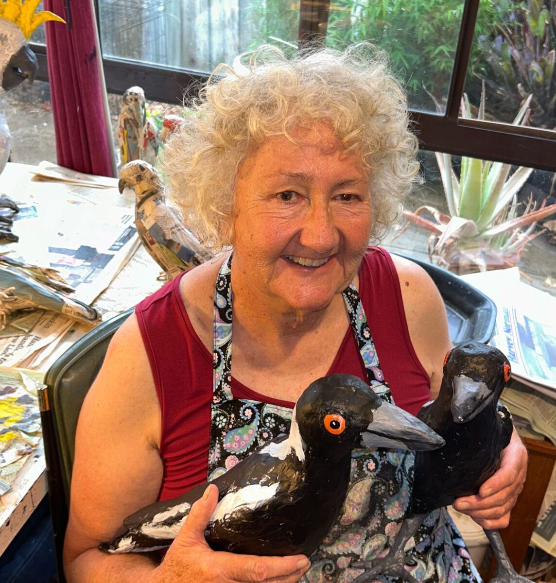Jane in her studio holding two of her magpie sculptures.