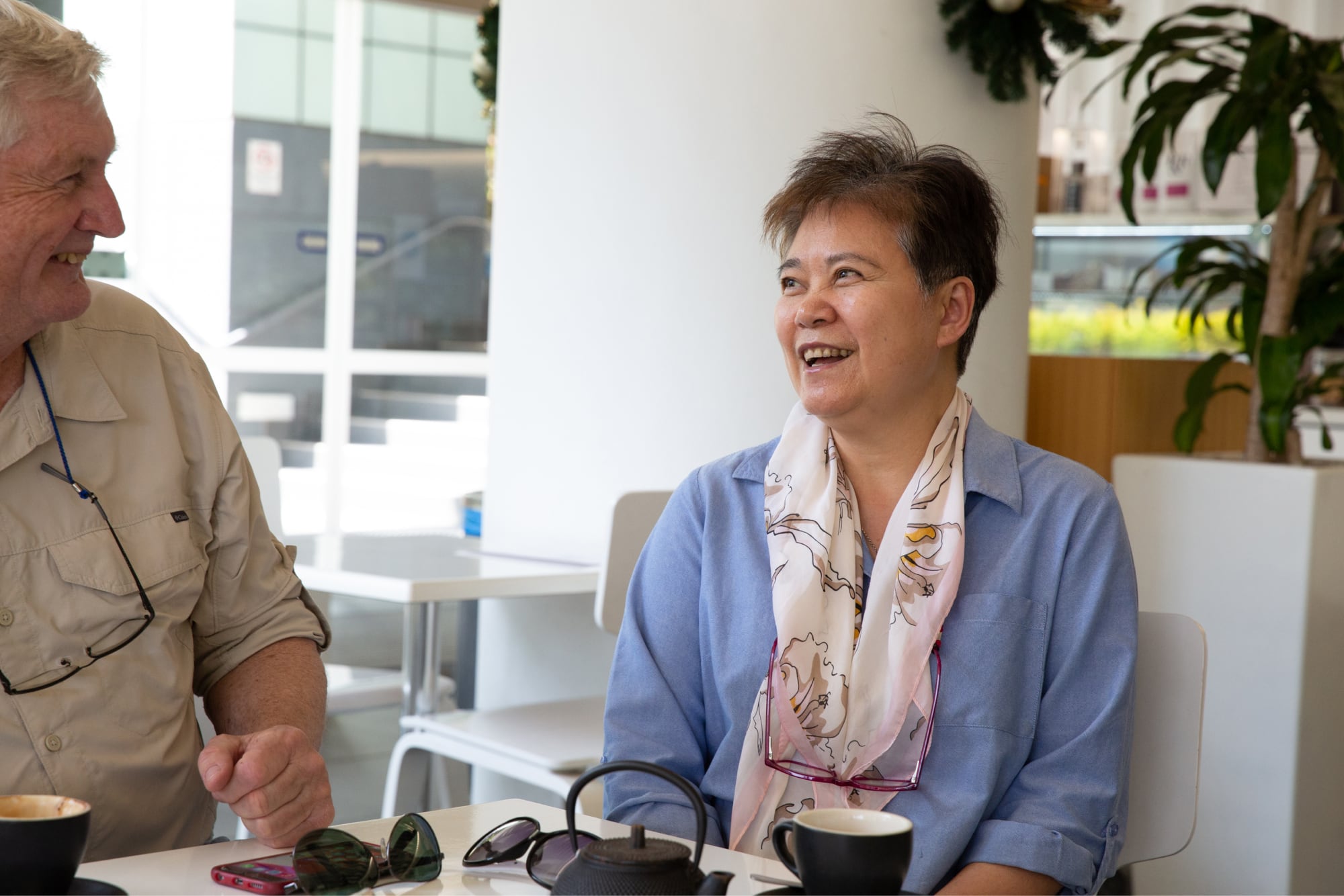 Two people sitting at a cafe smiling at each other.