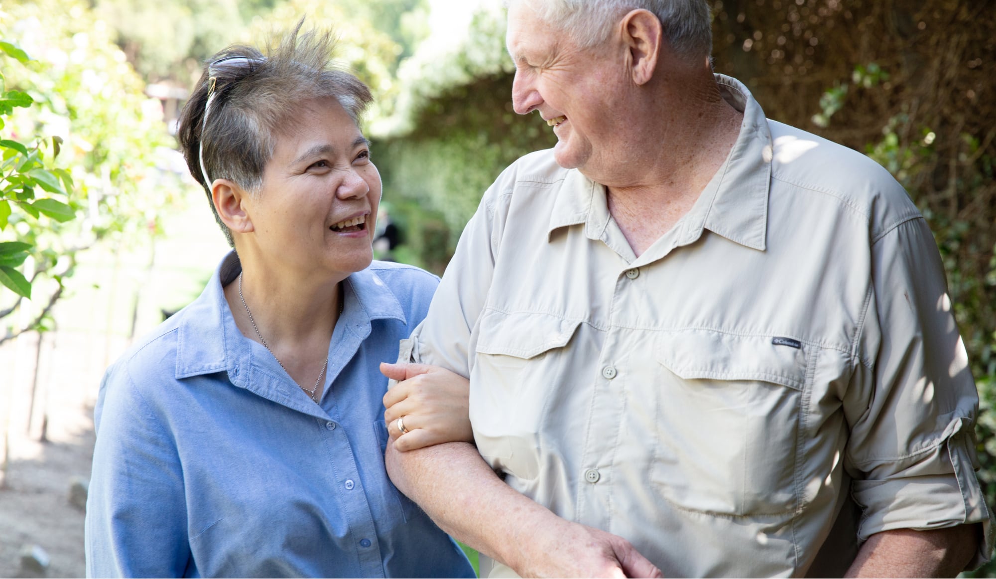 Two people outside looking at each other. One is holding the other at the elbow.