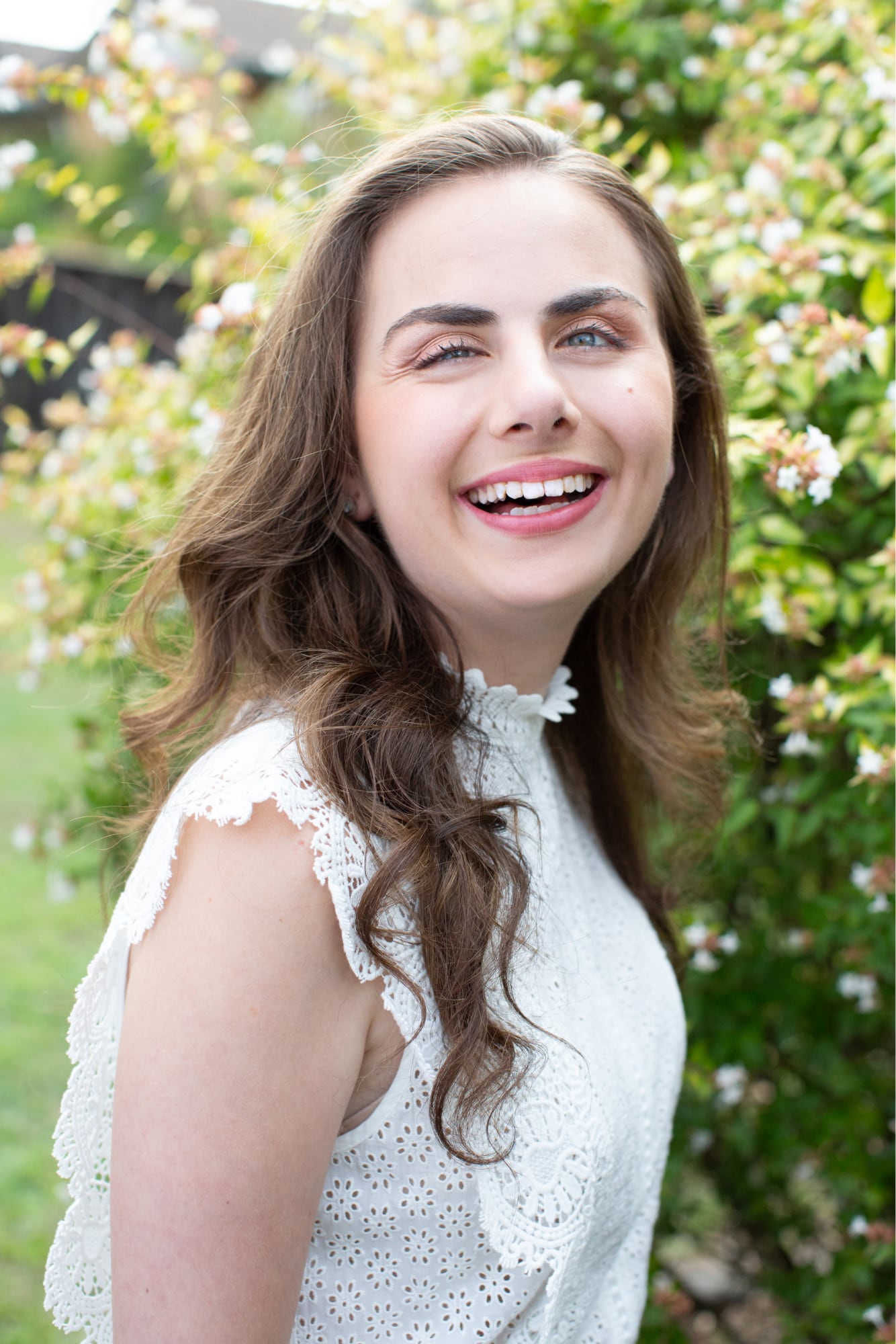 A person standing outside in a garden with a smile on their face looking at the camera.