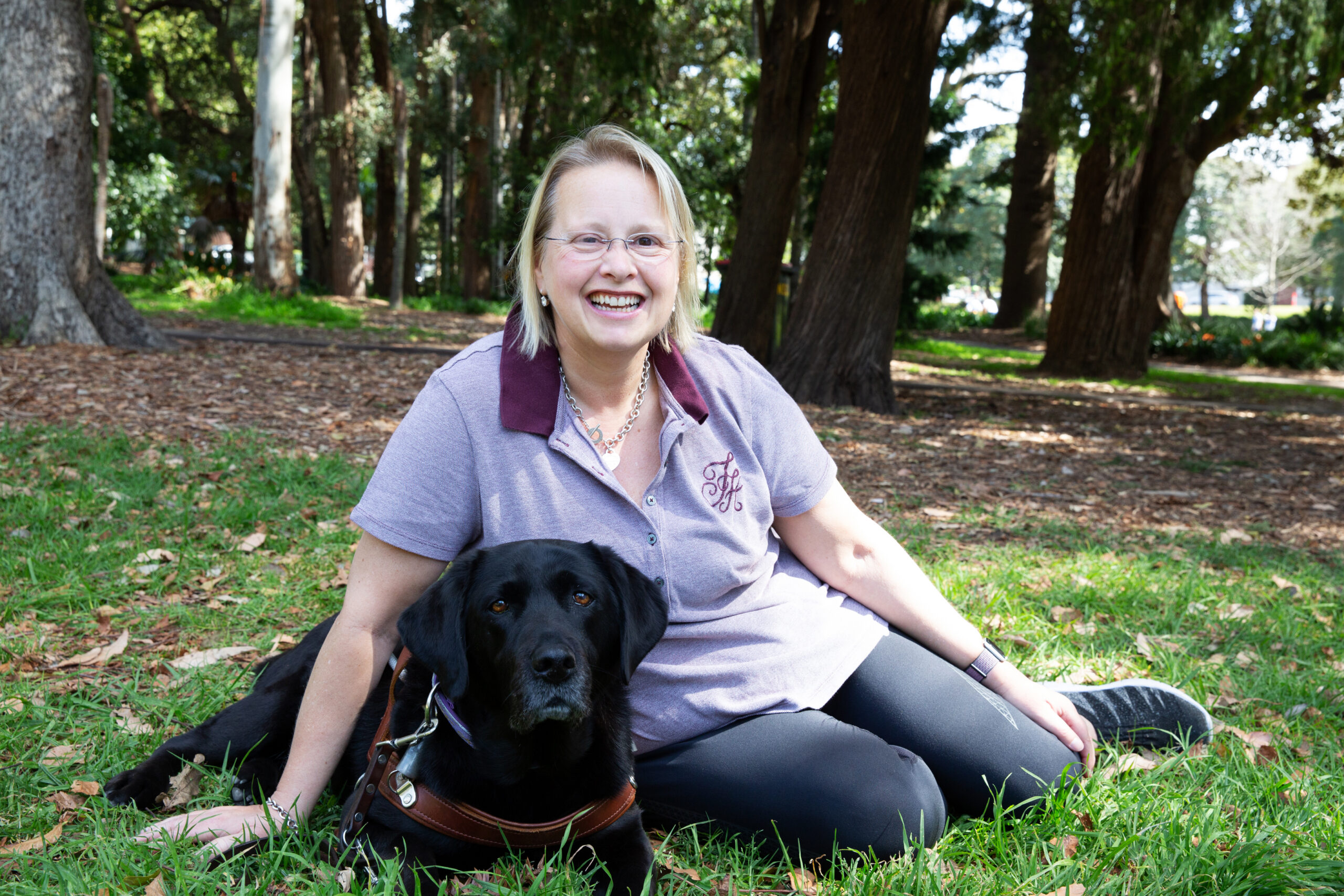 A person and their Guide Dog sitting together at a park.
