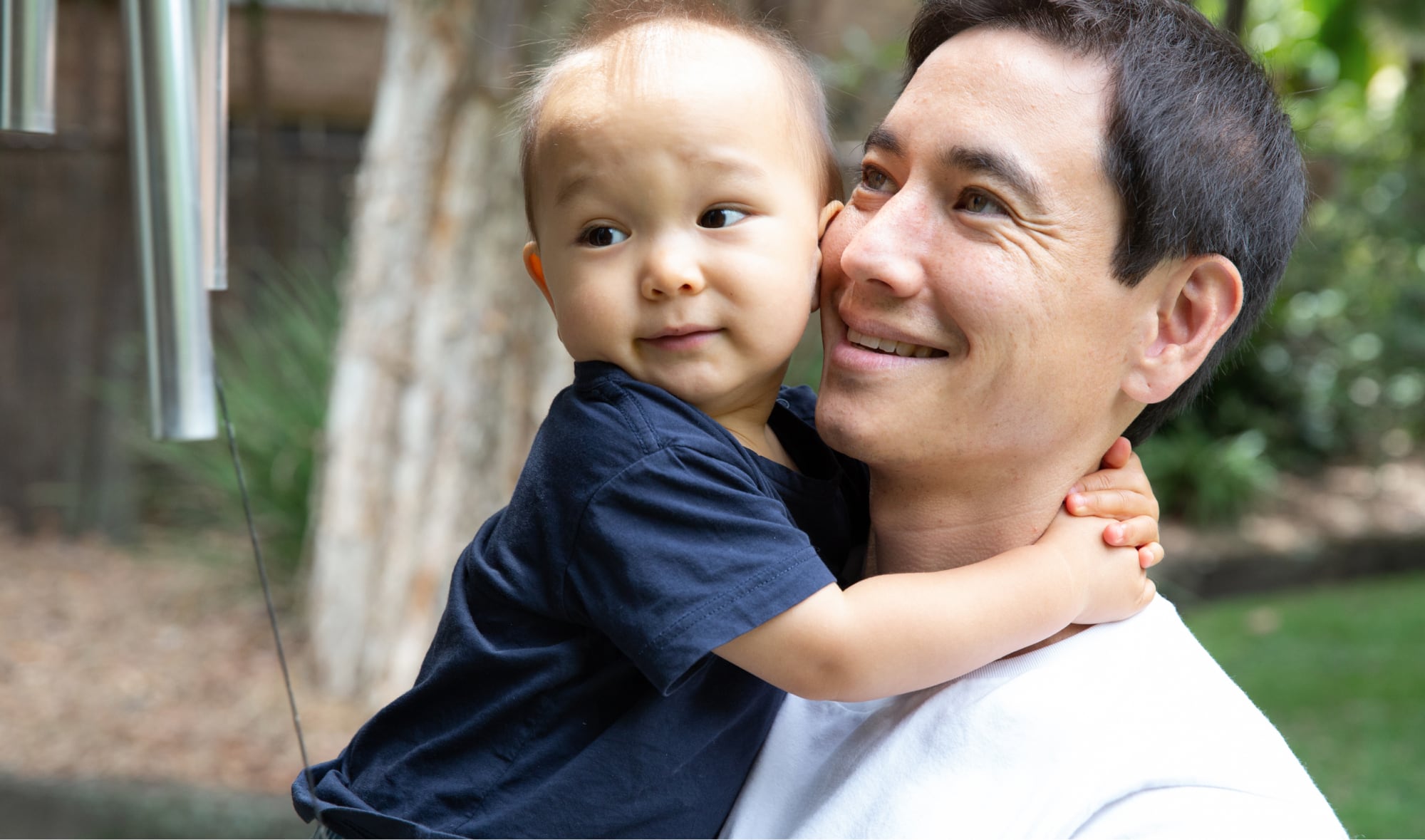 A father holding his toddler. The father has a smile on his face
