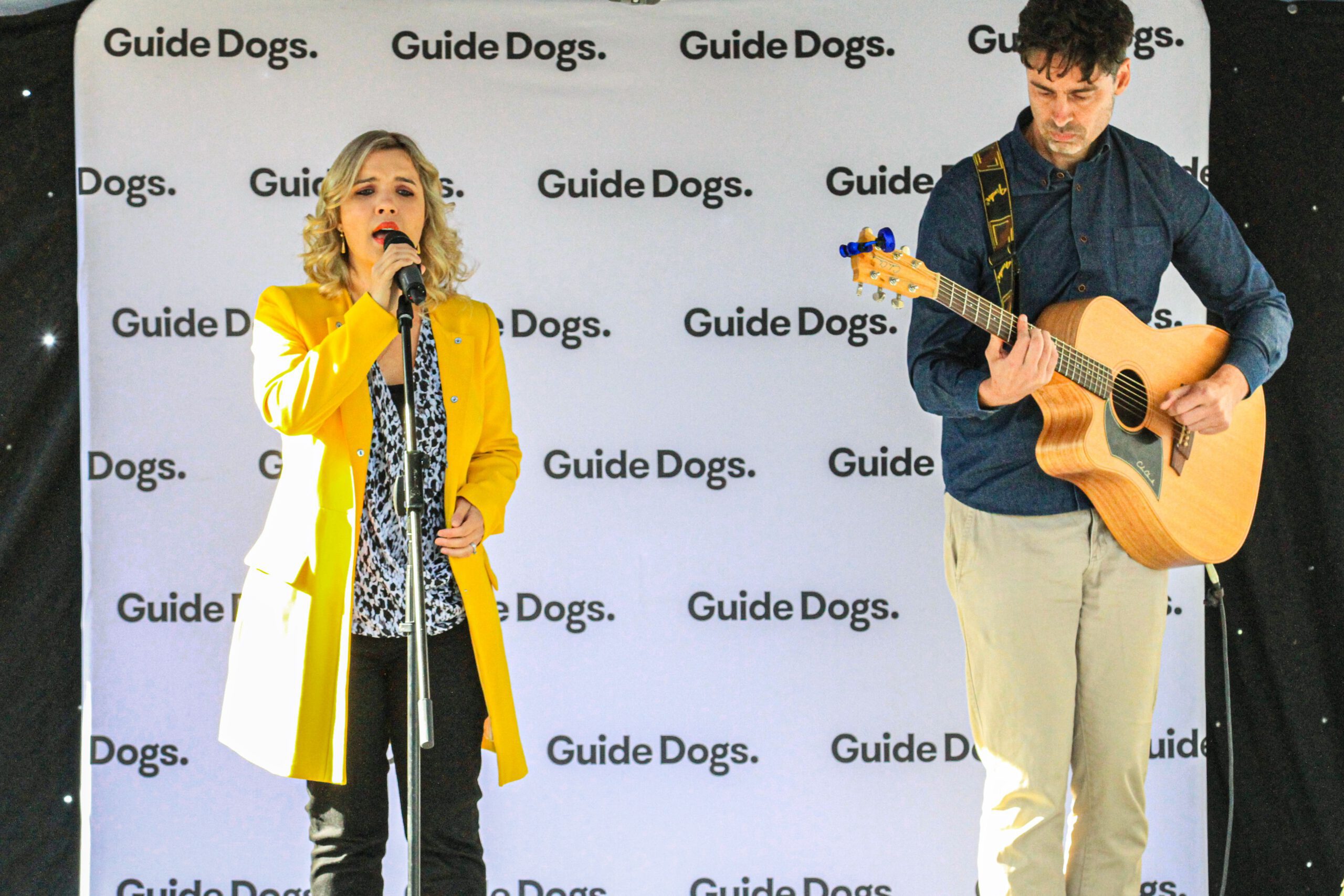 Rachael Leahcar onstage with accompanying guitar. 