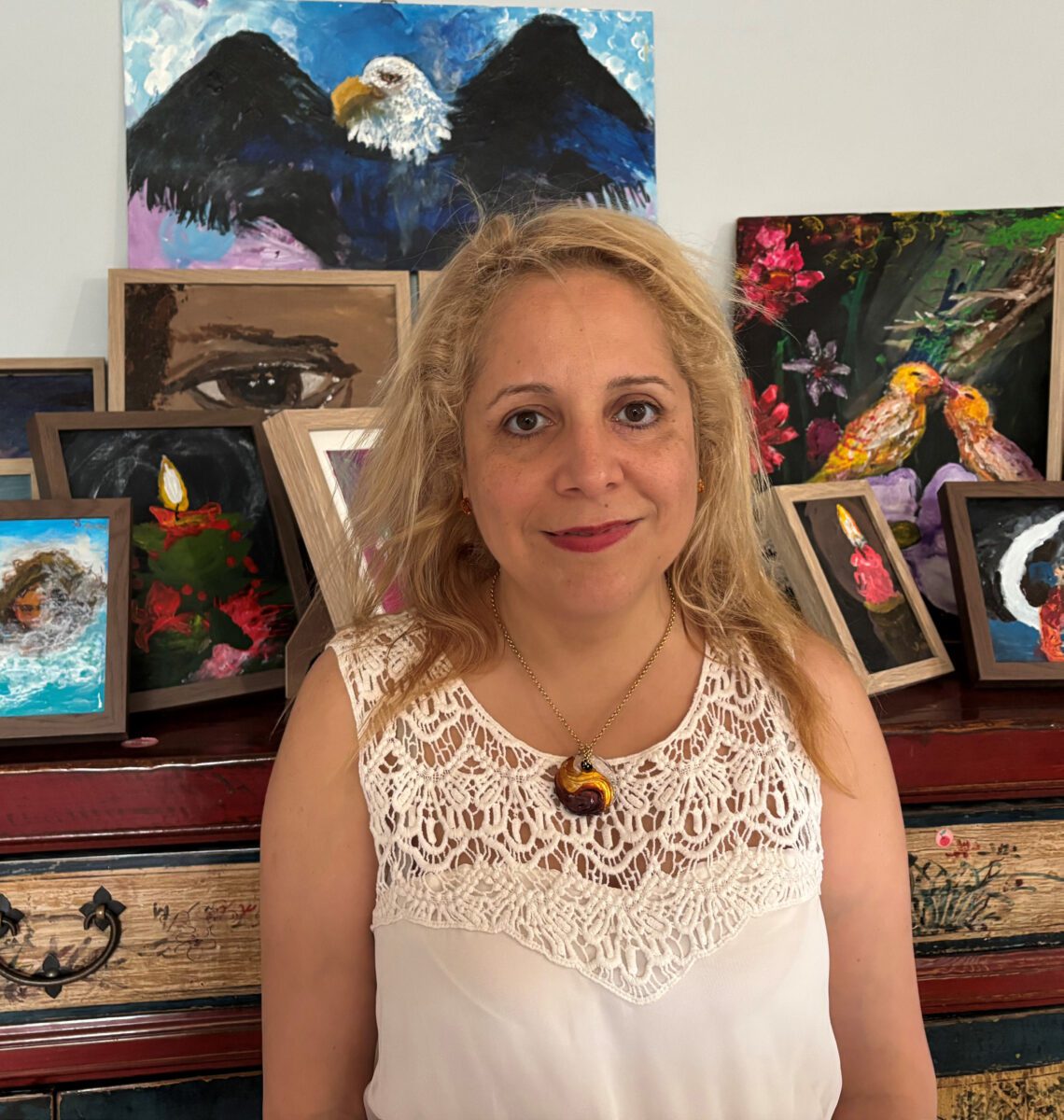 Sara standing in front of a mantle which has a number of her art pieces on display.