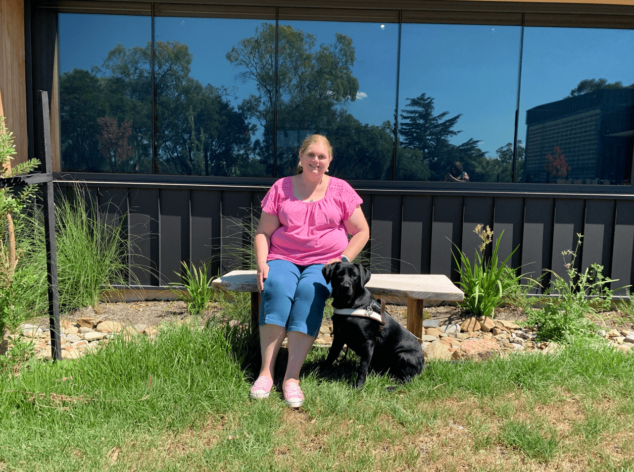 Tegan sitting with Ethel in Guide Dogs Victoria's sensory garden.
