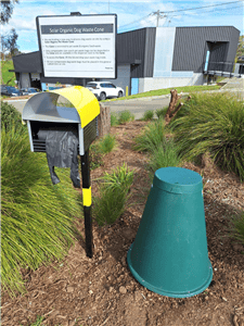 A yellow and black cornstarch bag dispenser with a green waste cone of the right, sits at the bottom of Picnic Hill.