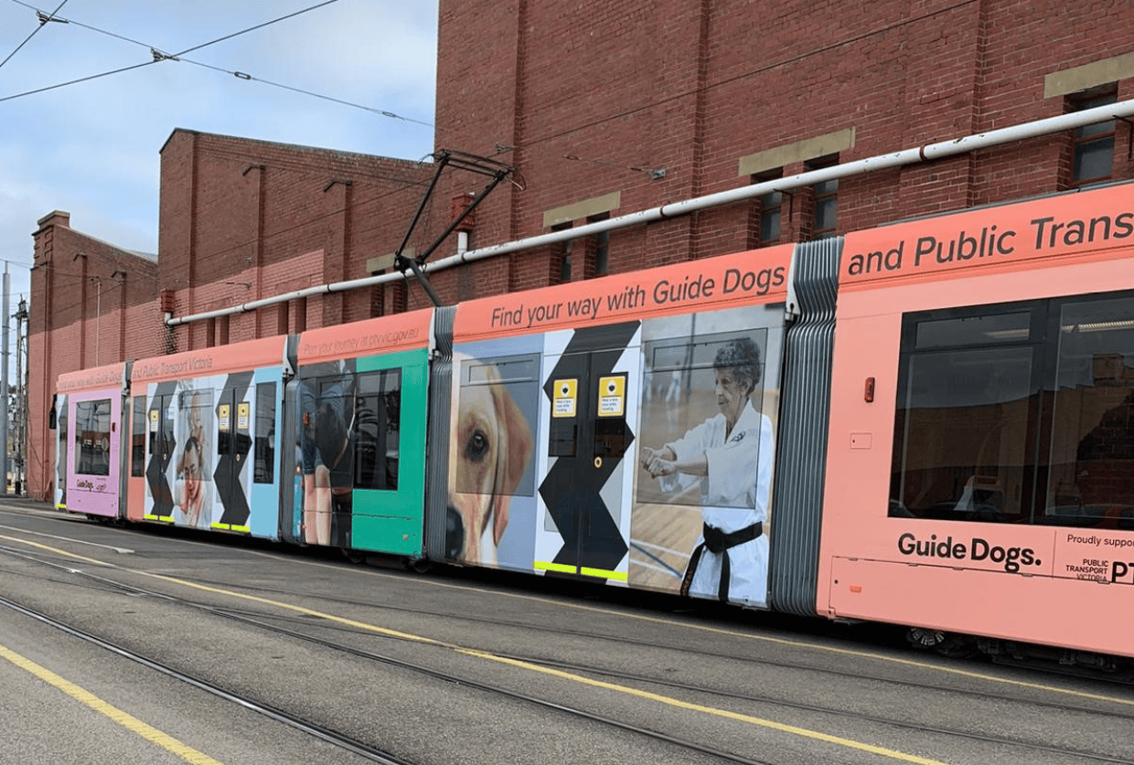 A tram wrapped in the new Guide Dogs branding with high contrast shapes on the doors and images of people and dogs