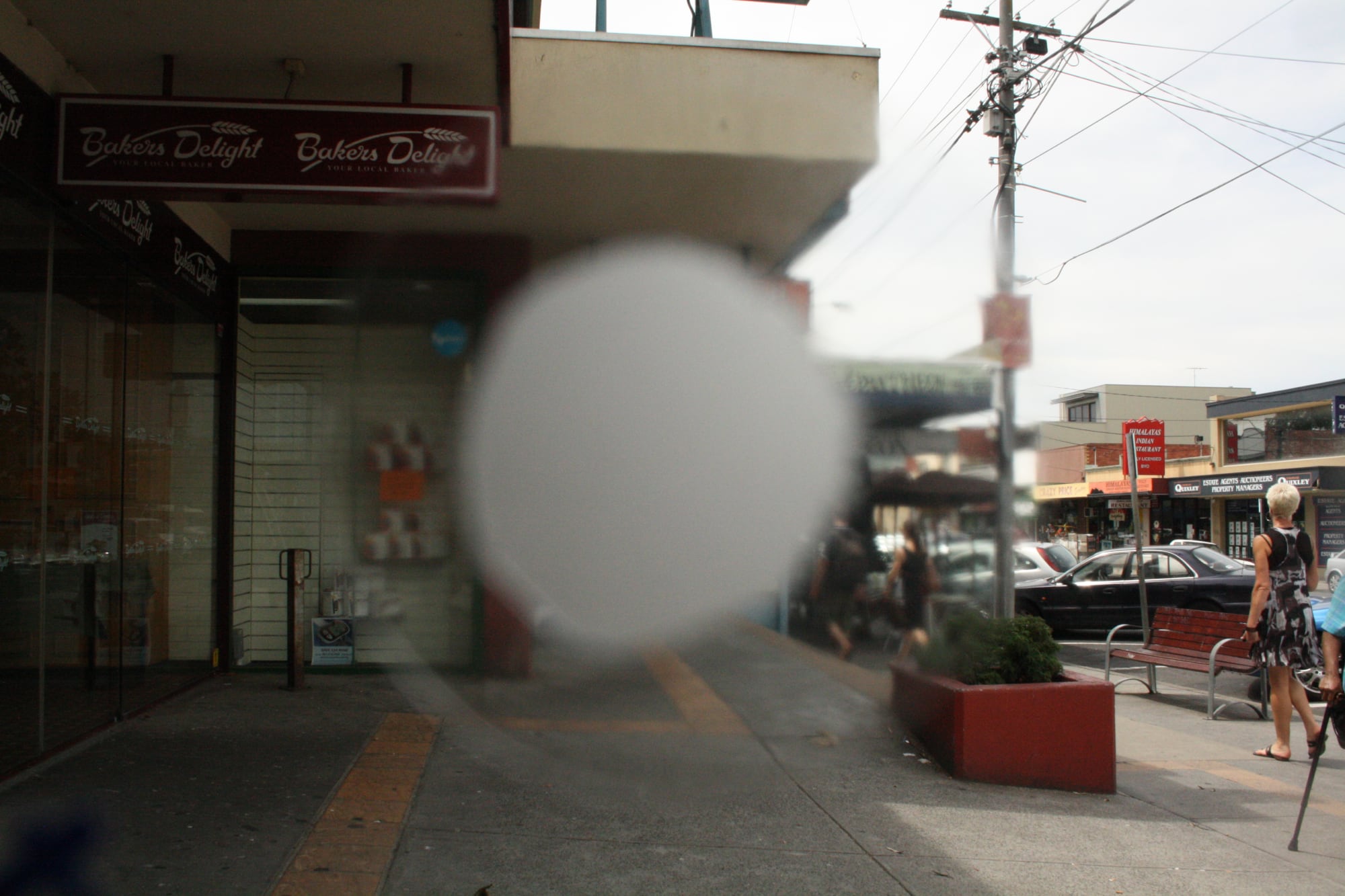 A busy footpath. The middle of the image is blurred with a white mark to portray how someone with macular degeneration might view it.