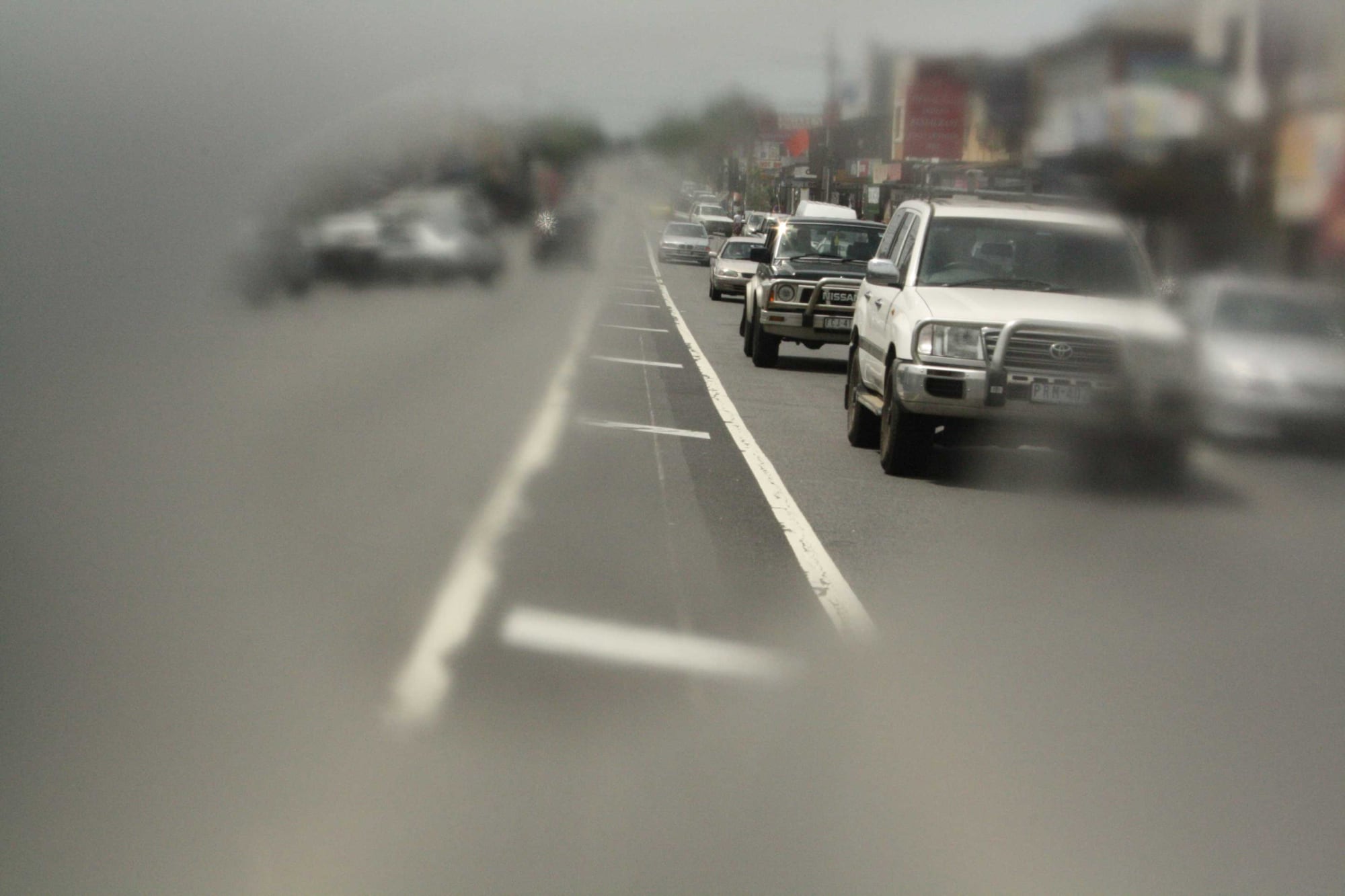 A busy road with cars on it. The outer edges of the image are blurred to portray how someone with retinitis pigmentosa might view it.