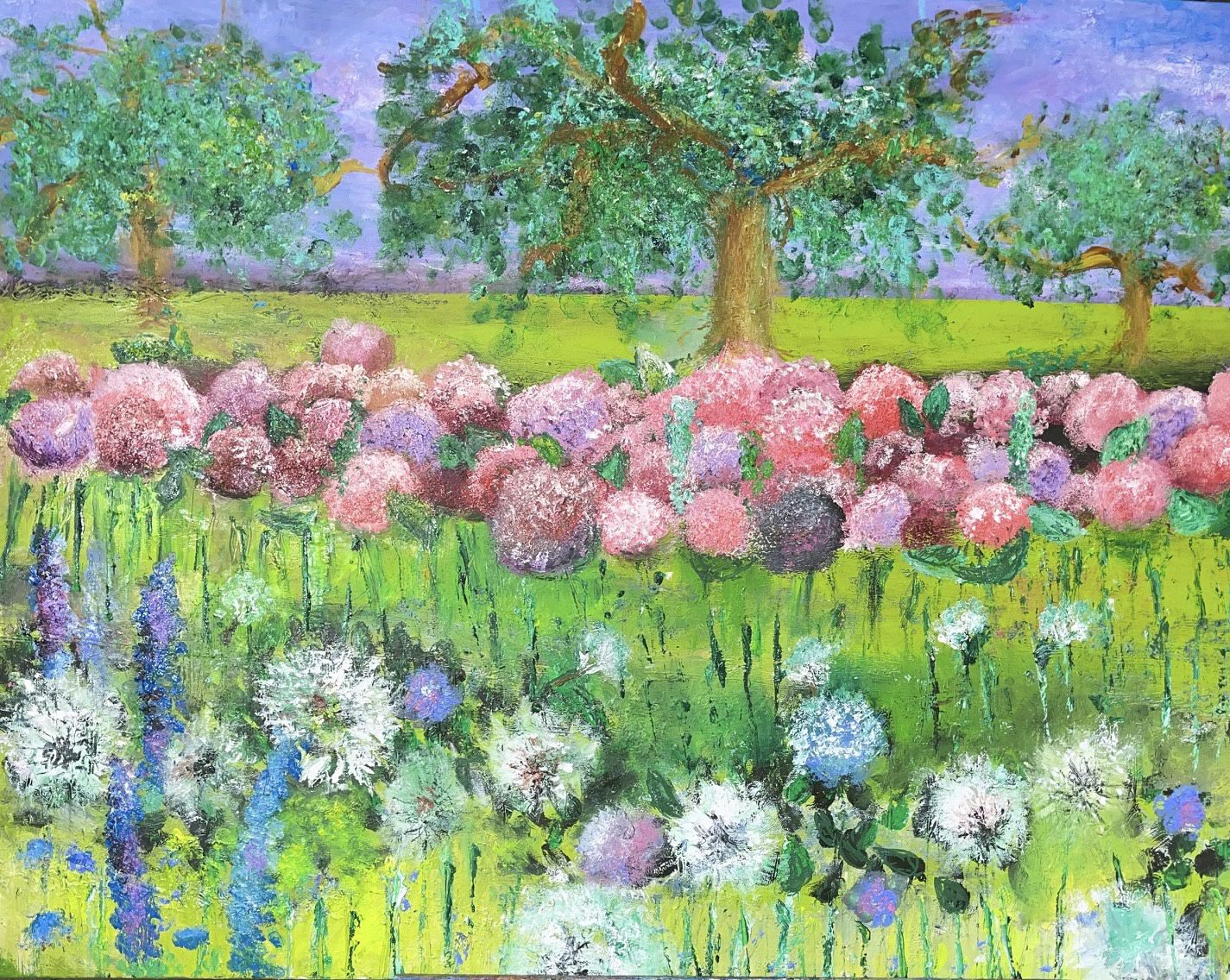 A vibrant garden scene with clusters of white, purple, and blue flowers in the foreground, pink and purple hydrangeas in the middle, and three large green trees against a bright blue sky in the background.