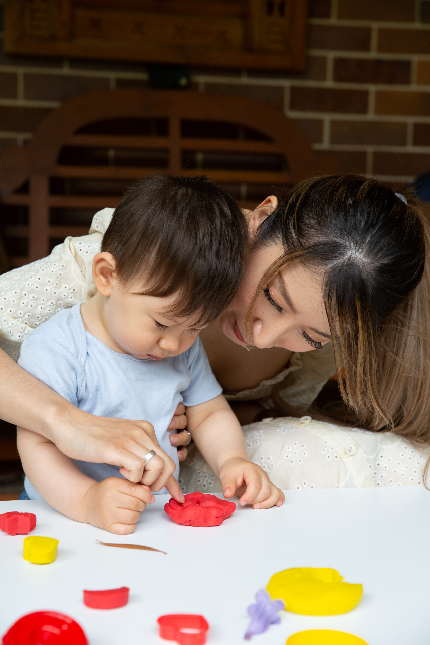 A mother and toddler playing with play dough.