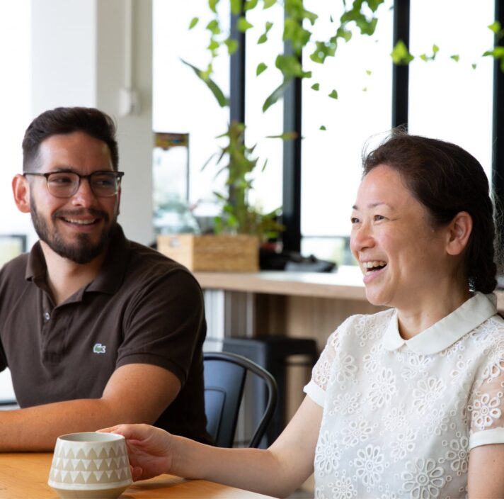 Two people sitting at cafe table. Both people are smiling.