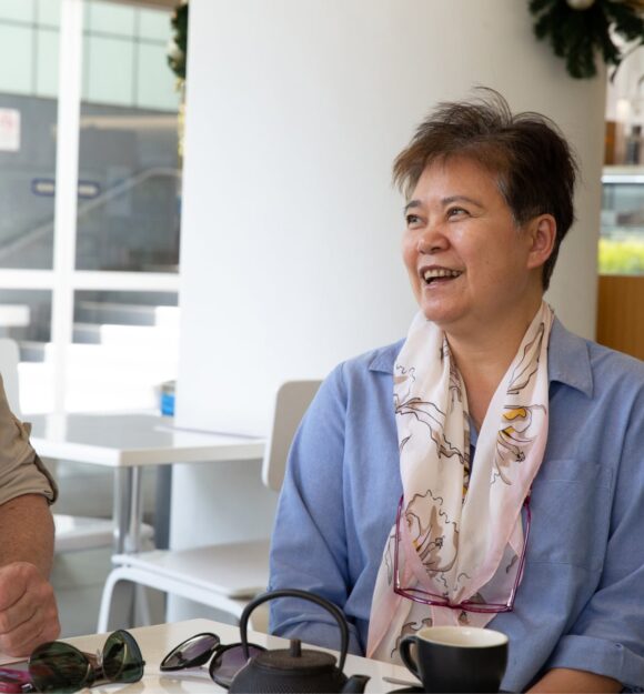 Two people sitting at a cafe smiling at each other.