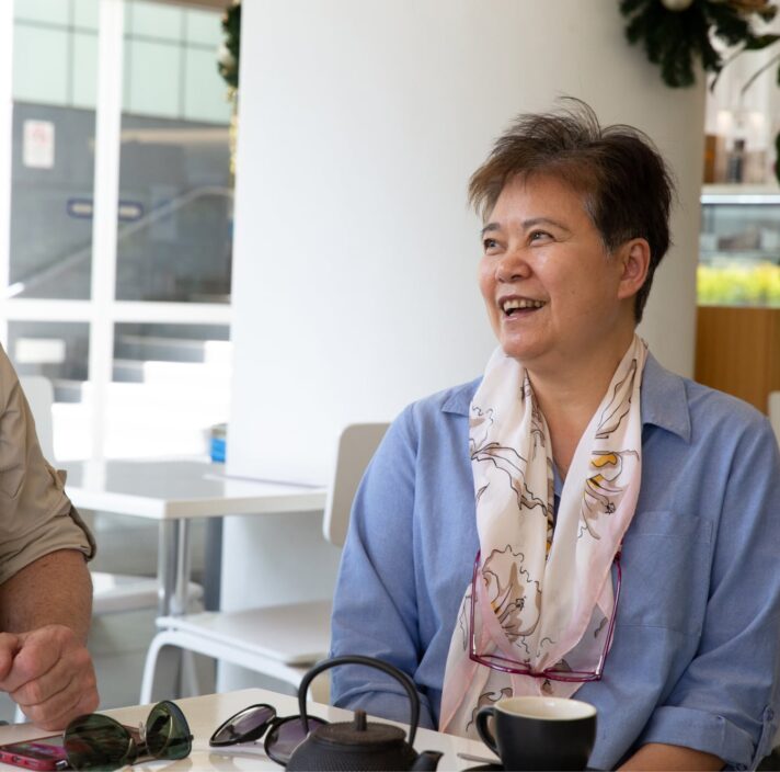 Two people sitting at a cafe smiling at each other.