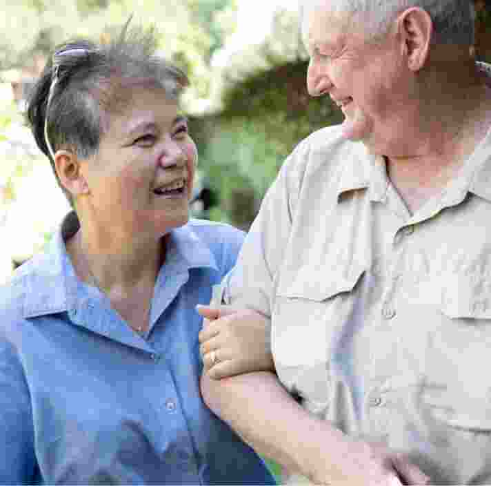 Two people outside looking at each other. One is holding the other at the elbow.