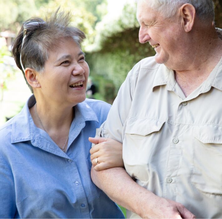 Two people outside looking at each other. One is holding the other at the elbow.