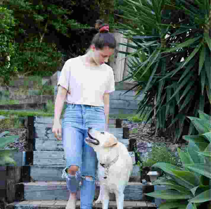 A person walking down some stairs with their yellow labrador dog. The dog and handler and looking at each other.