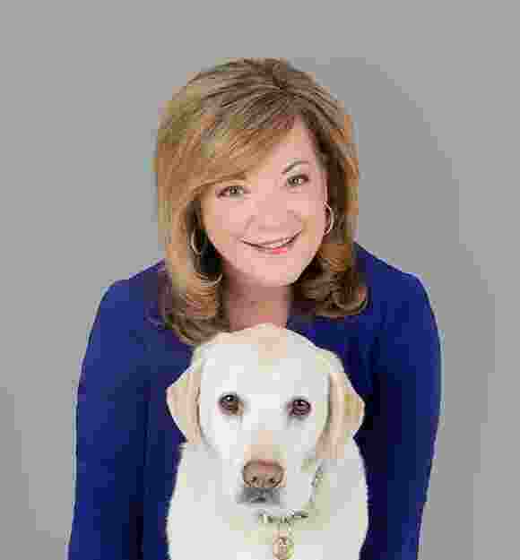 Guide Dogs Victoria Chief Executive Officer, Karen Hayes with a yellow labrador dog. Karen is behind the dog and both are looking at the camera.