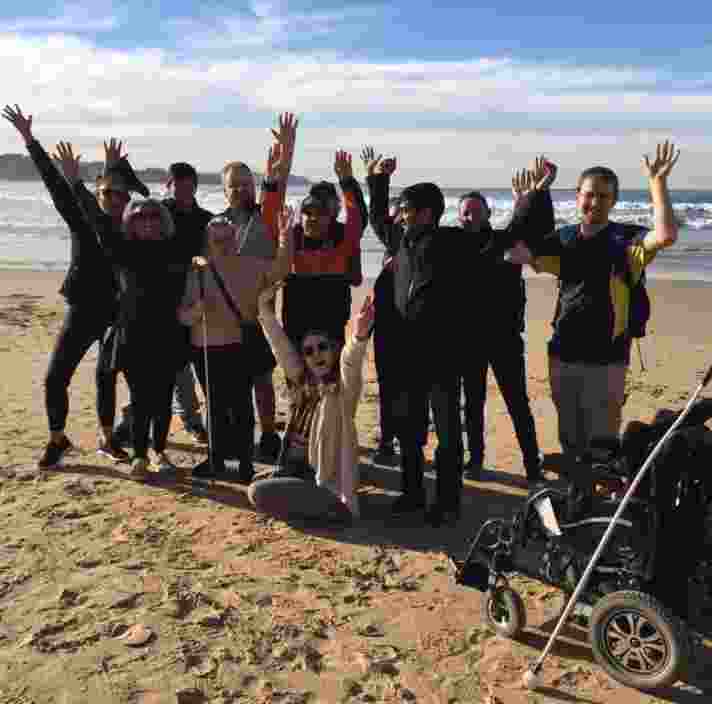 A group of people on a beach facing the camera with their arms in the air