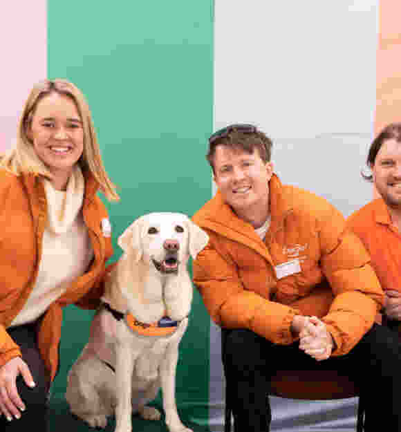 Expr3ss staff members crouch next to a yellow Labrador