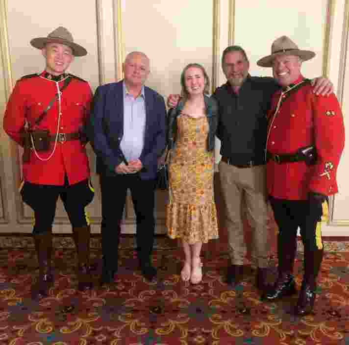 Guide Dogs staff Gary, Elisha and Aaron standing in between two Canadian mounted police wearing the Red Serge uniform