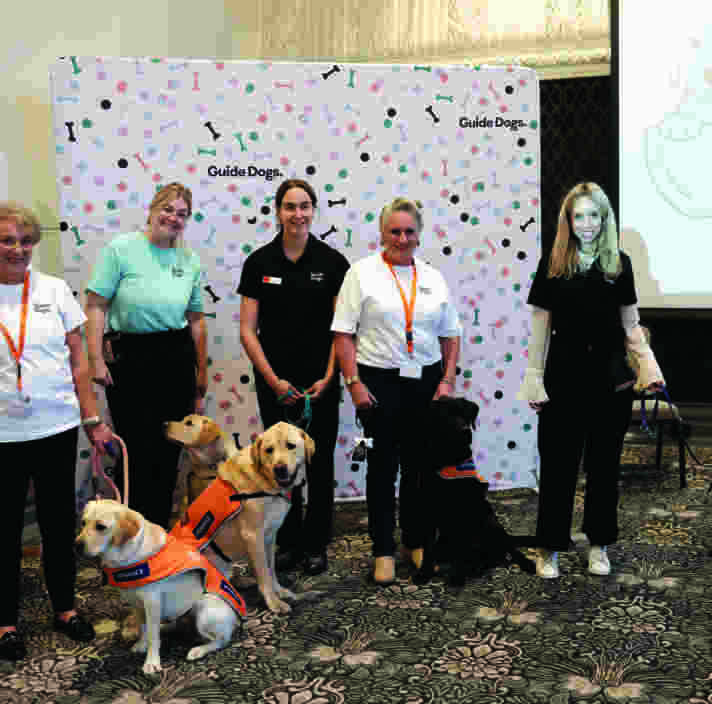 A group of people in front of a banner at the International Guide Dog Day celebration